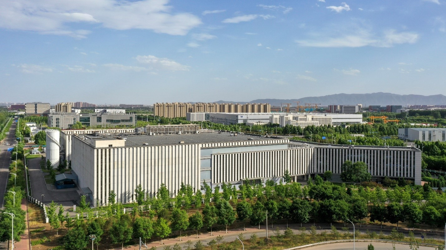 Photograph of a huge data center taking up the majority of a flat landscape dotted with trees in the foreground