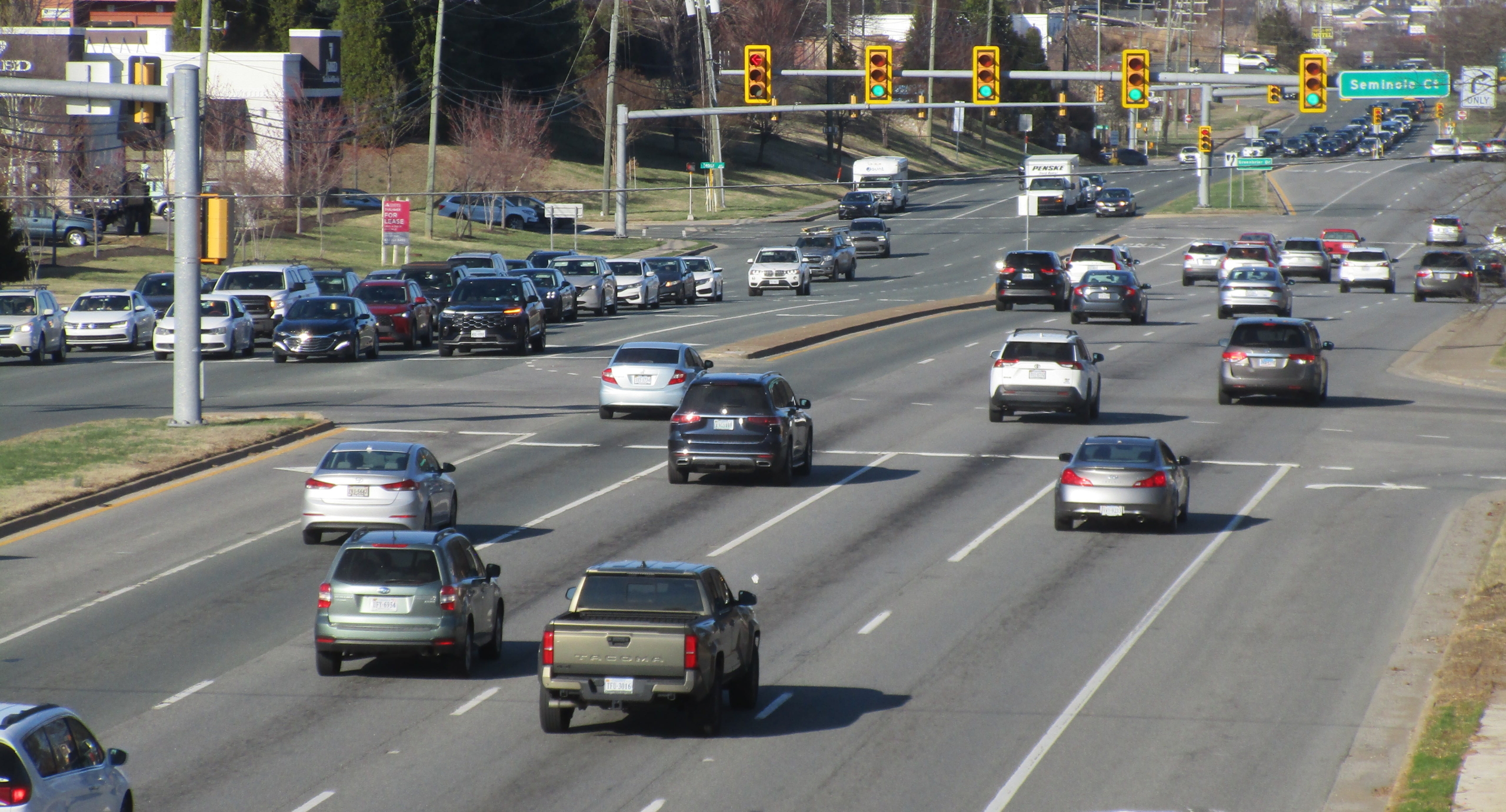 An 8-lane road with stoplights and many cars.
