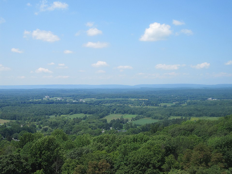 aerial view of forests, fields, and small mountains in the distance