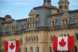 Parliament building in Canada, with two large Canadian flags hanging from windows.