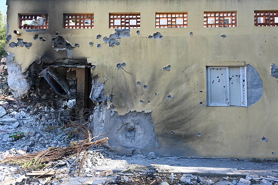 Yellow wall of a building with one corner completely destroyed and a pile of rubble.
