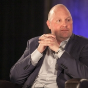 Andreessen sits on an armchair with his hands clasped, wearing a suit and a serious face.