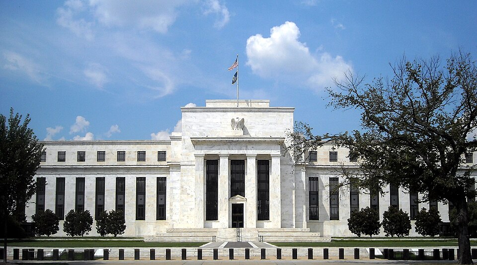 The white building with a U.S. flag flying over it and a blue sky in the background