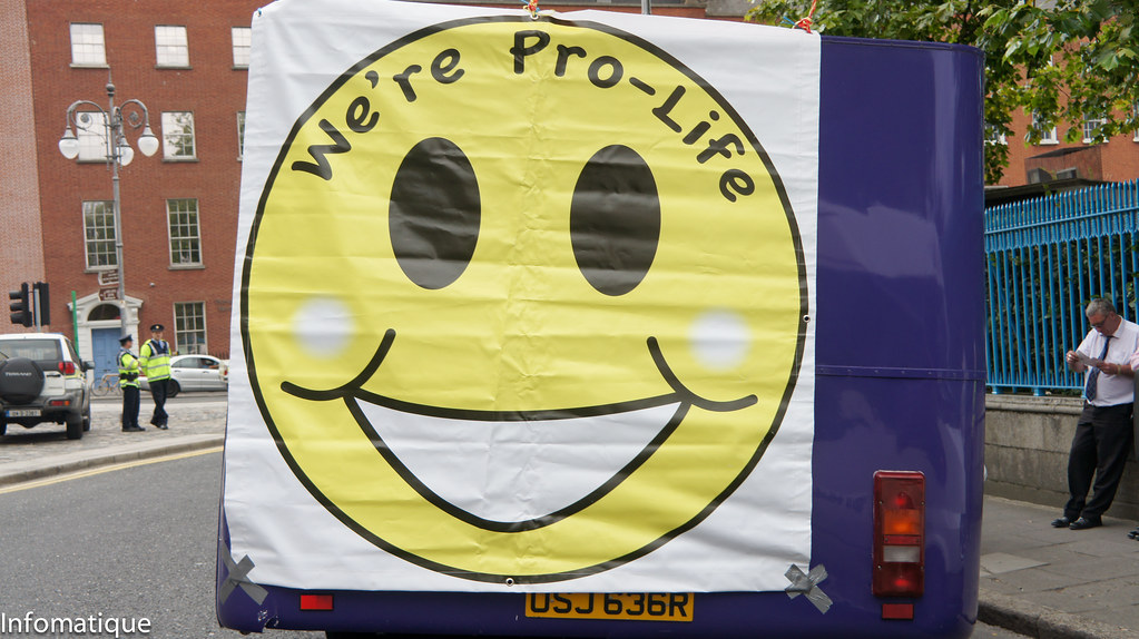 A purple bus with a large banner covering the back with a smiley face reading "We're pro-life."