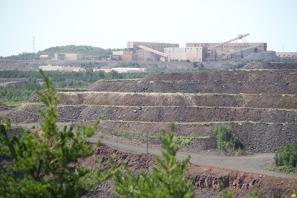 huge open-pit mine with sprawling processing facility in the background