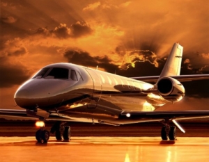 private jet, parked, with orange sky behind it