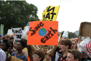 Image of young protesters, with one holding a sign that says "Save Earth"