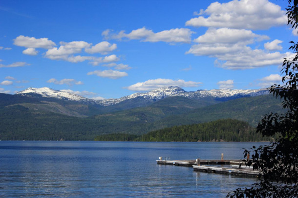 a blue lake with snow-capped mountains and blue skies in the background
