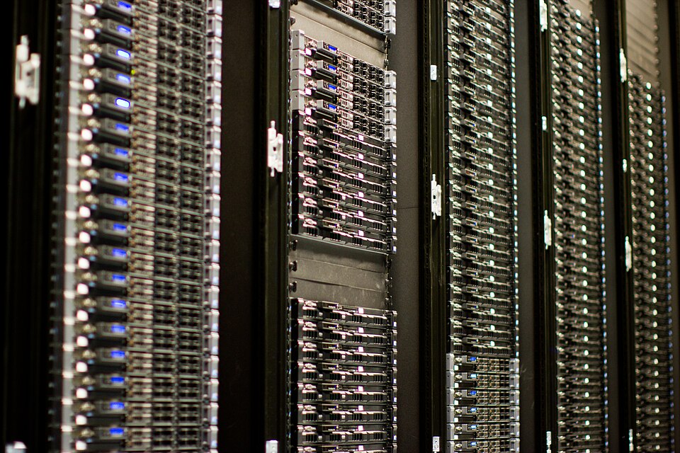 A close up of five Wikimedia Foundation server racks, with blue, pink, and green lights.