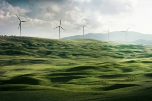 Five wind turbines overlooking a green, grass-covered landscape