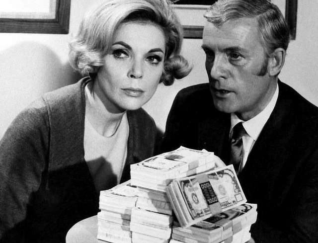 Two actors hover over a pile of cash, looking suspicious.