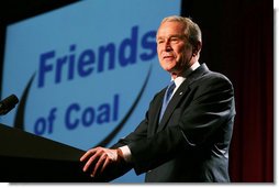 George W. Bush stands at a podium, talking and smiling