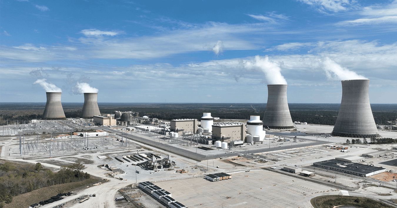 A sprawling nuclear-energy facility with white smoke rising from four massive reactors.