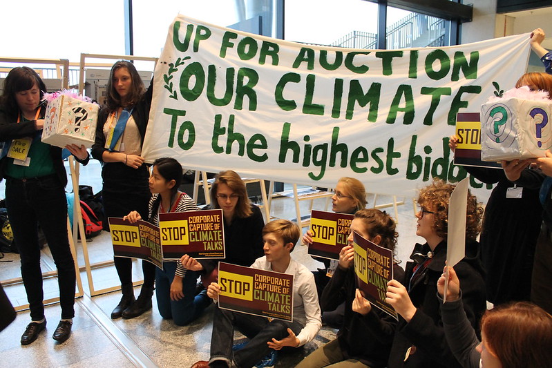 group of young people, some standing and holding a banner, some sitting and holding signs