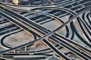 Aerial view of a sprawling highway interchange, with black roads contrasting against surrounding brown dirt.