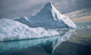 image of an iceberg in Greenland, reflected against the water