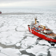 Two icebreaker ships cutting through ice in the Arctic.