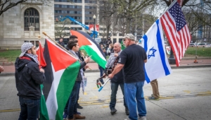 Palestinians face off against poeple holding Israeli and US flags in a street