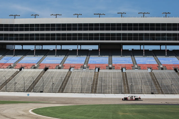 Empty NASCAR stadium with one car racing the track.