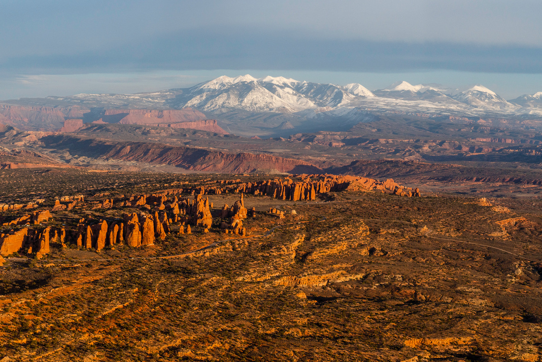 vast landscape, with red canyons in the foreground and snowy mountains in the background