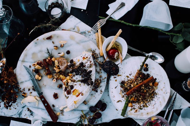 Close-up of a table full of plates, utensils, and napkins. The plates have been picked through but still contain a significant amount of food.