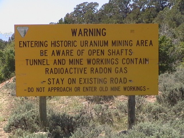 A large yellow sign on a bush-covered hillside
