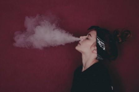 Woman exhaling smoke; pigouvian taxes are conducive to a steady state economy