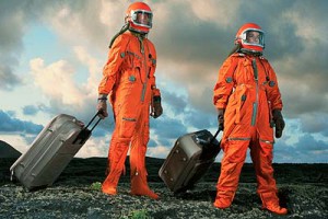 People walking in space suits with luggage. 