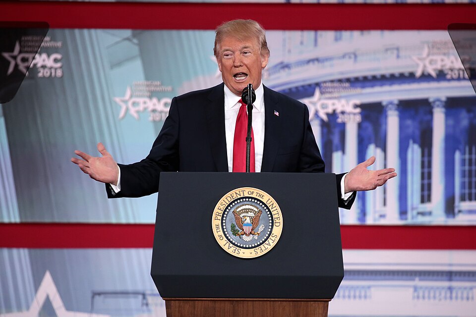 Trump speaks at a podium with his hands out.