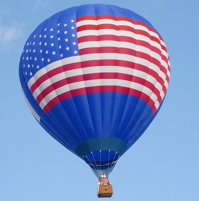 Hot air balloon with an American flag on it against a blue sky.